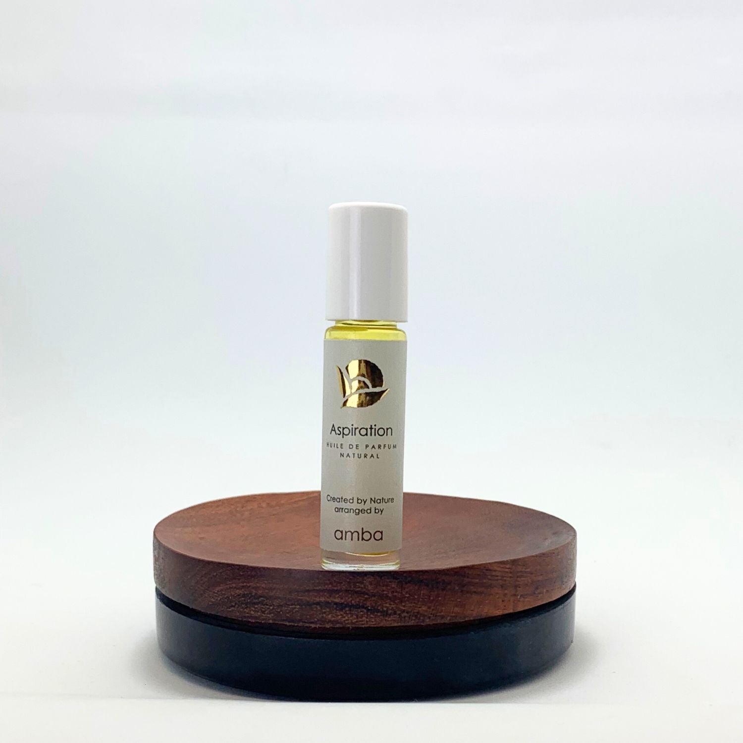Naturparfum Aspiration als Roll on auf Holzsockel vor weißem Hintergrund