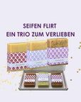 Drei Seifenstücke nebeneinander und in einer Schachtel aus dem Seifenset Seifenflirt ein Trio zum Verlieben