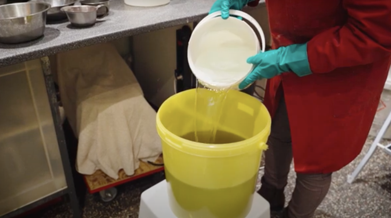 Öl wird in Eimer gegossen bei Herstellung der Pflanzenölseifen