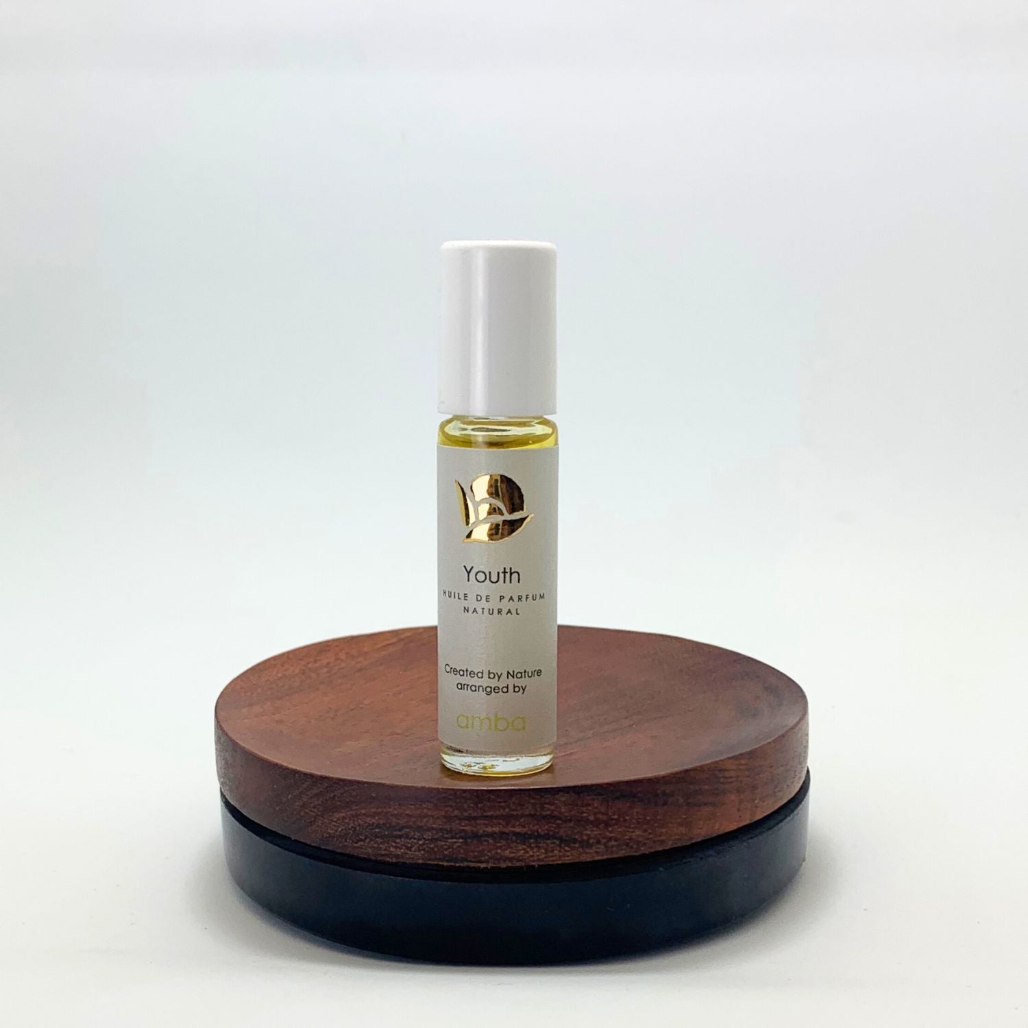 Naturparfüm Youth Roll On Flasche auf Holzsockel vor weißem Hintergrund