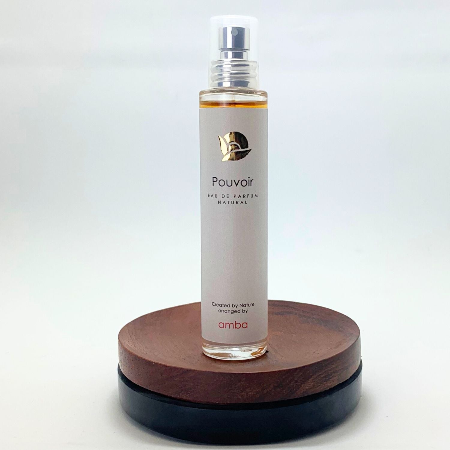 Flakon Naturparfum von amba Pouvoir auf Holzsockel vor weißem Hintergrund
