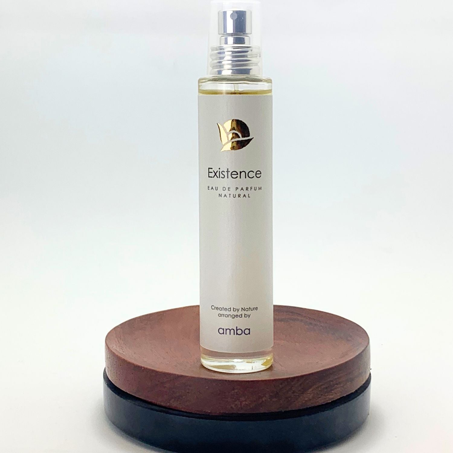 Flakon von amba „Existence“ Naturparfum auf Holzsockel vor weißem Hintergrund