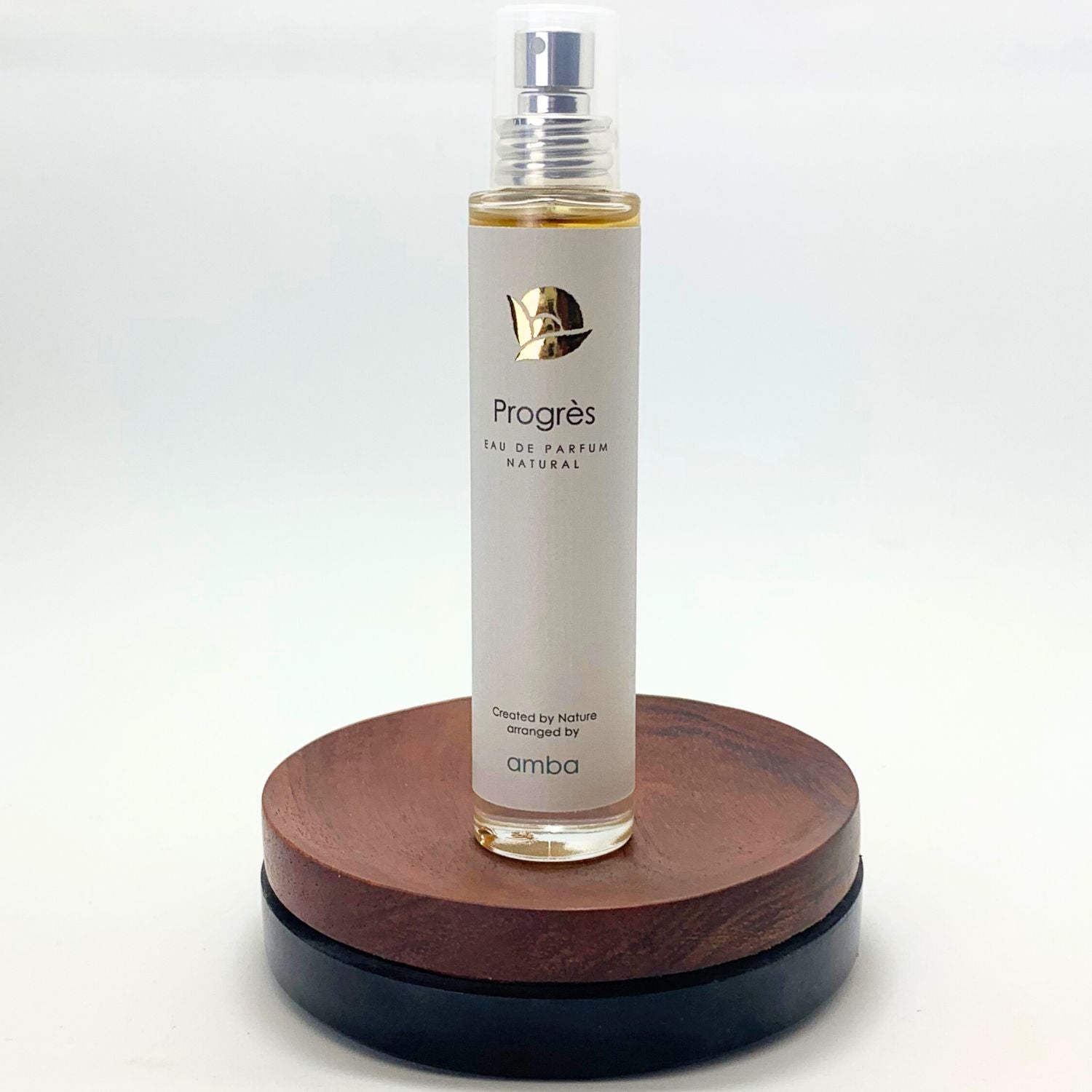 Flakon Naturparfüm Progres auf braunem Holzsockel vor weißem Hintergrund