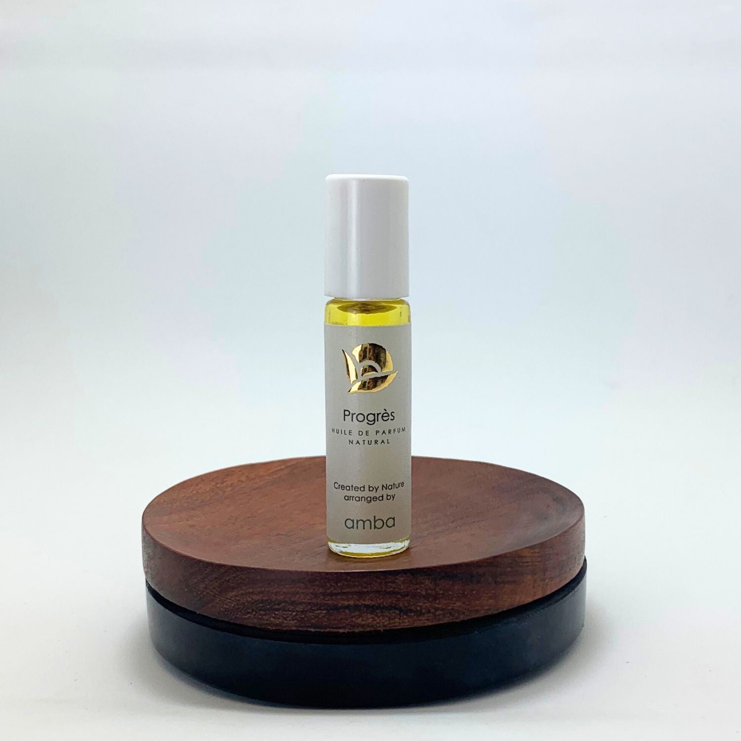 Progres amba Roll on Flasche auf braunem Holzsockel vor weißem Hintergrund