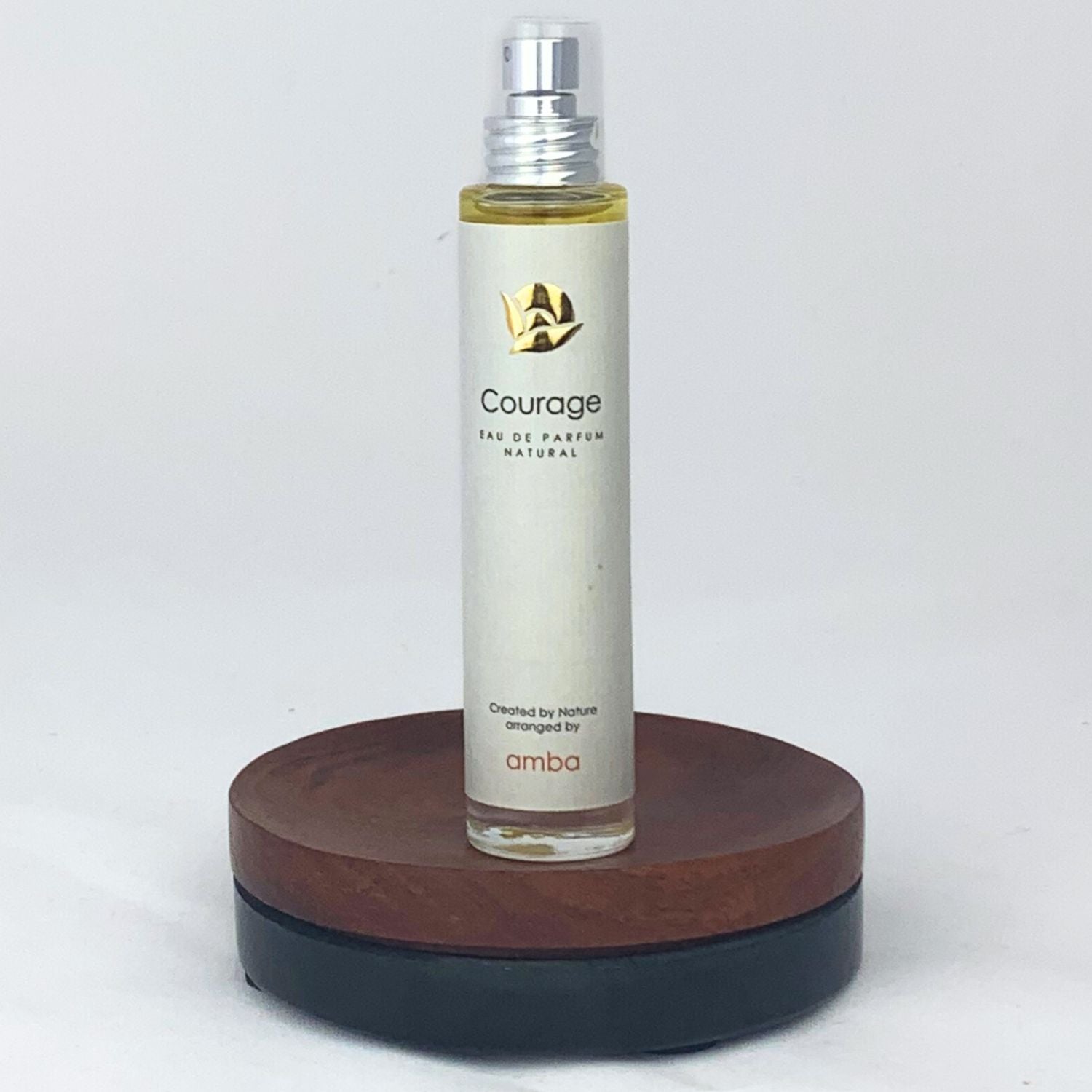 Flakon des Courage Naturparfums von amba auf Holzsockel vor weißem Hintergrund