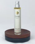 Flakon des Courage Naturparfums von amba auf Holzsockel vor weißem Hintergrund