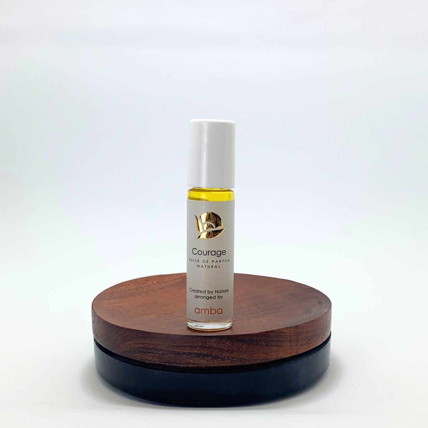 Roll-on des Courage Naturparfums von amba auf Holzsockel vor weißem Hintergrund