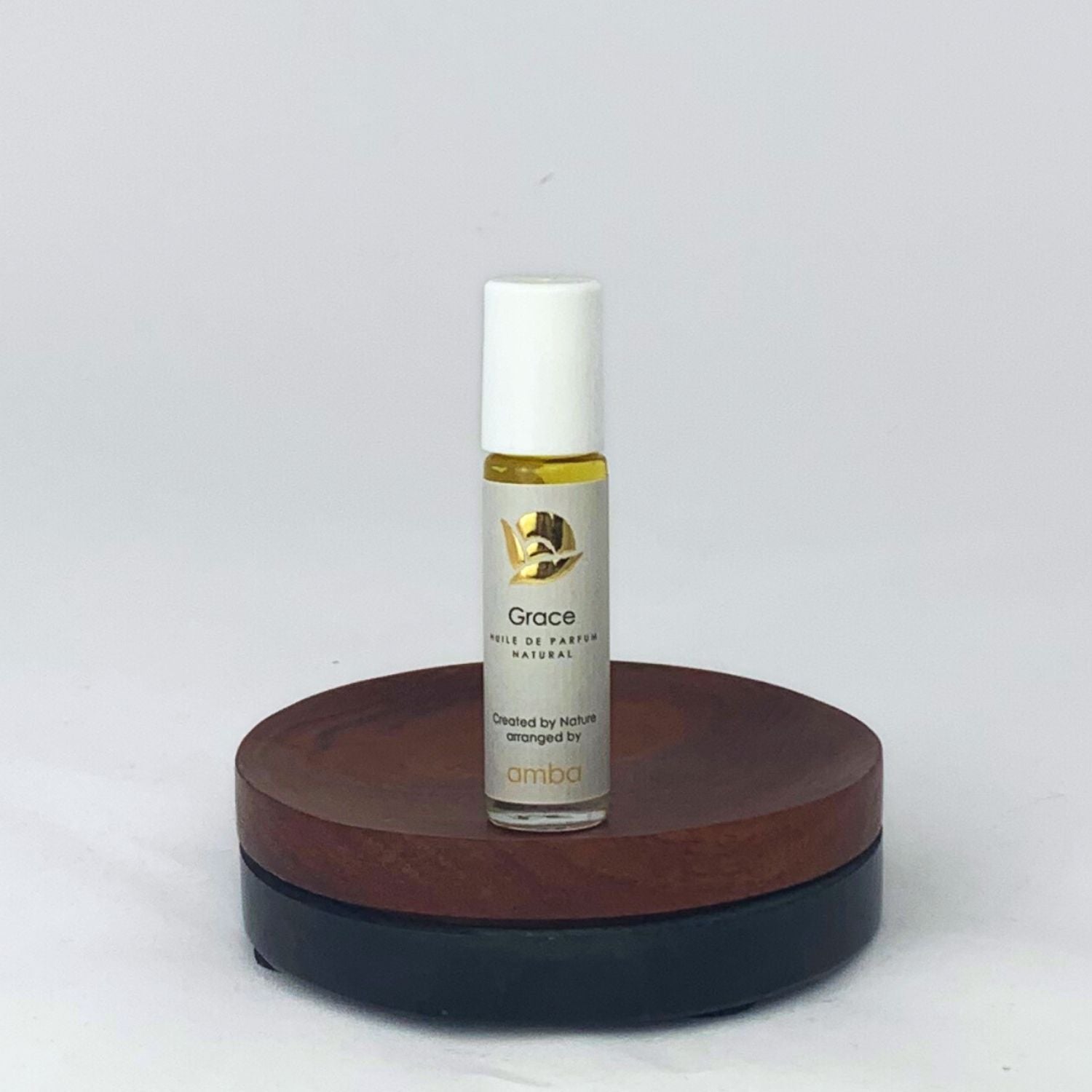 Roll-on des Grace Naturparfums von amba auf Holzsockel vor weißem Hintergrund