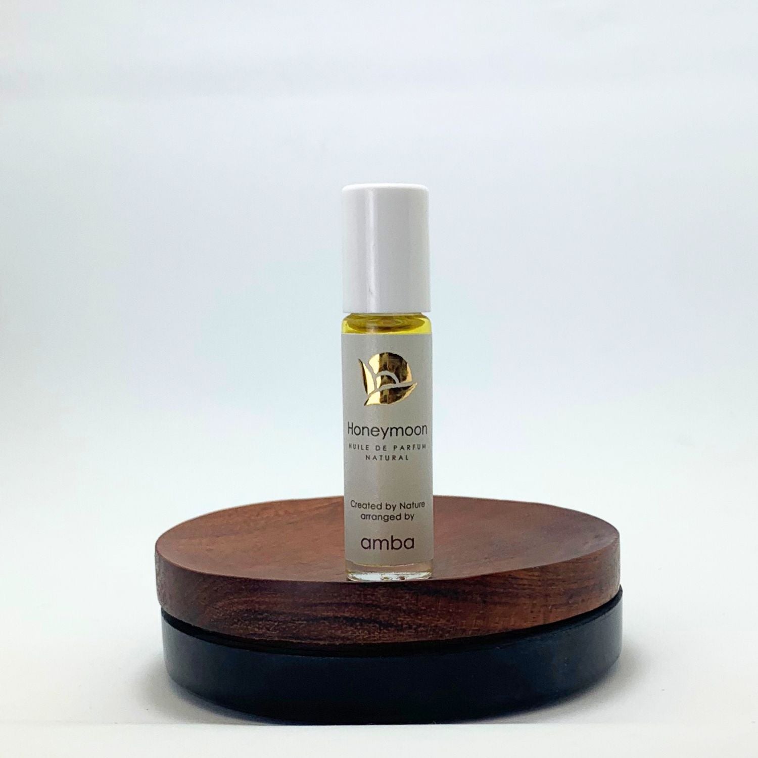 Roll-on Naturparfum Honeymoon von amba auf Holzsockel vor weißem Hintergrund
