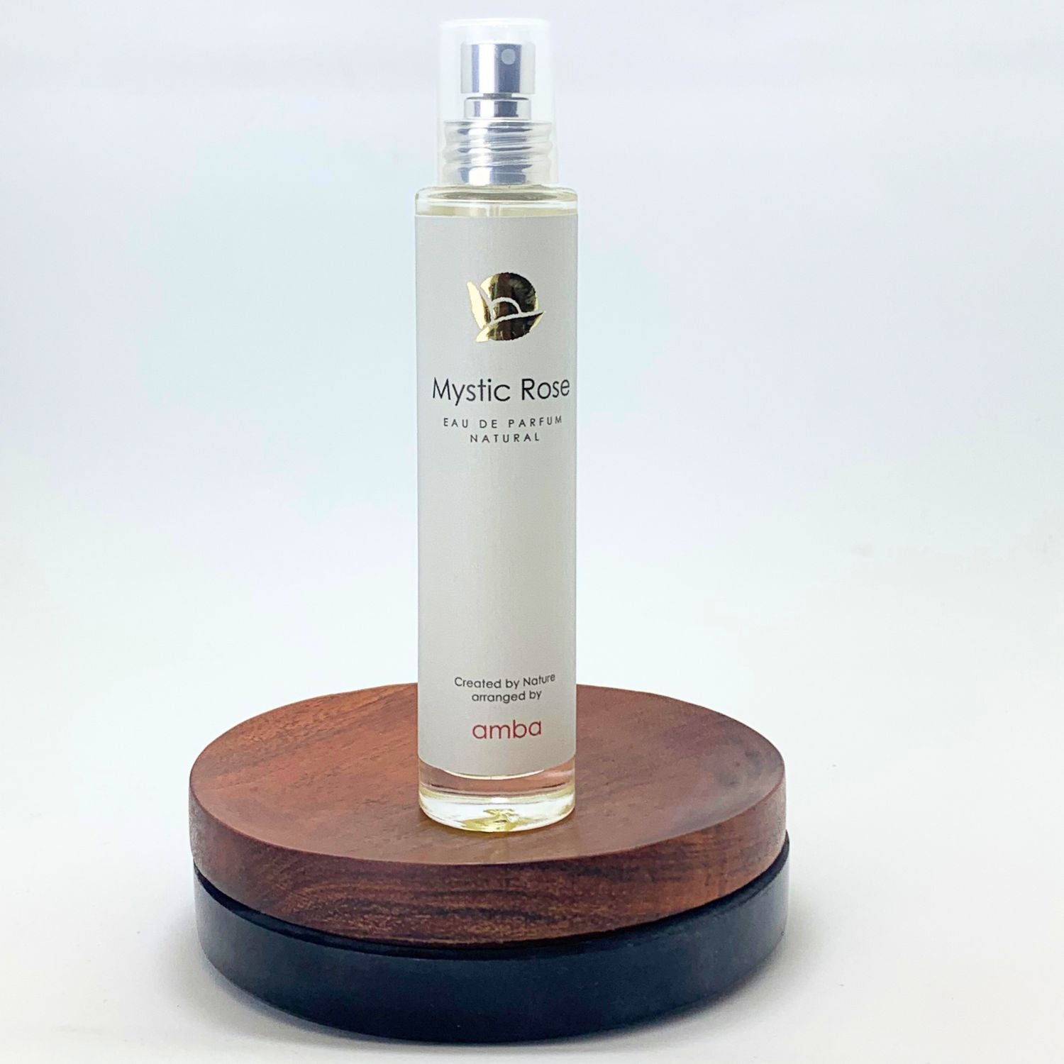 Flakon des Mystic Rose Naturparfums von amba auf Holzsockel vor weißem Hintergrund