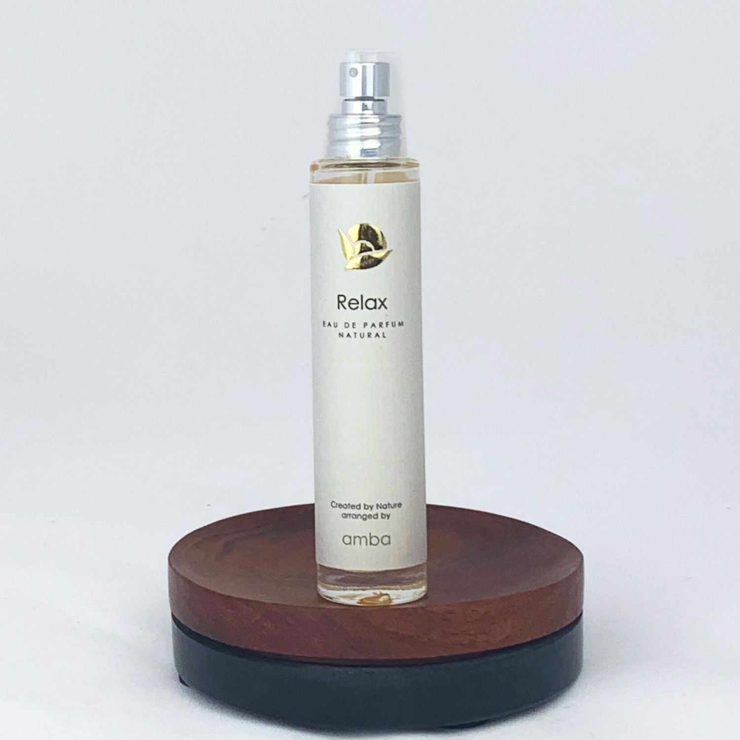 Flakon des Relax Naturparfums von amba auf Holzsockel vor weißem Hintergrund