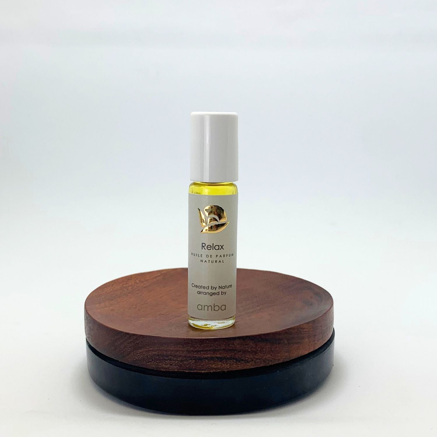 Roll-on des Relax Naturparfums von amba auf Holzsockel vor weißem Hintergrund