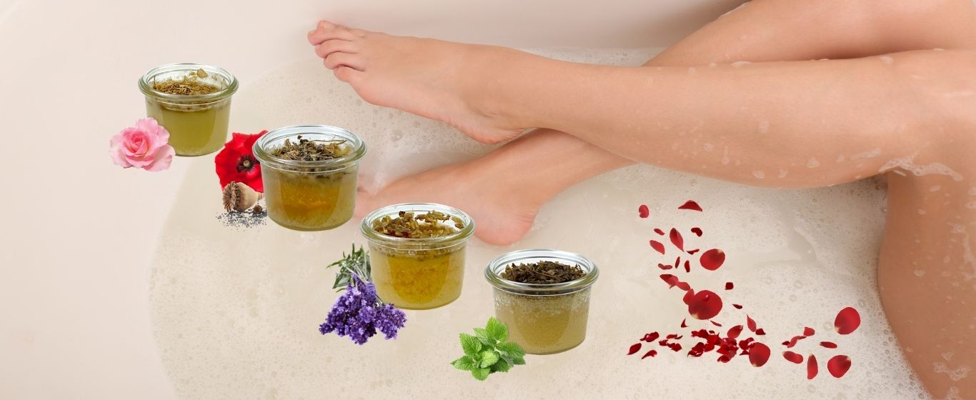 Jemand liegt in der Badewanne. Man sieht nur die Beine und vier amba Honigbäder-Lavendel-Honeymoon-Melisse-Rosengarten 