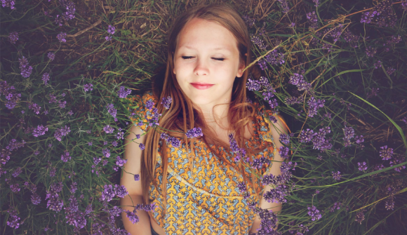 Mädchen liegt in einer Lavendel Wiese mit geschlossenen Augen