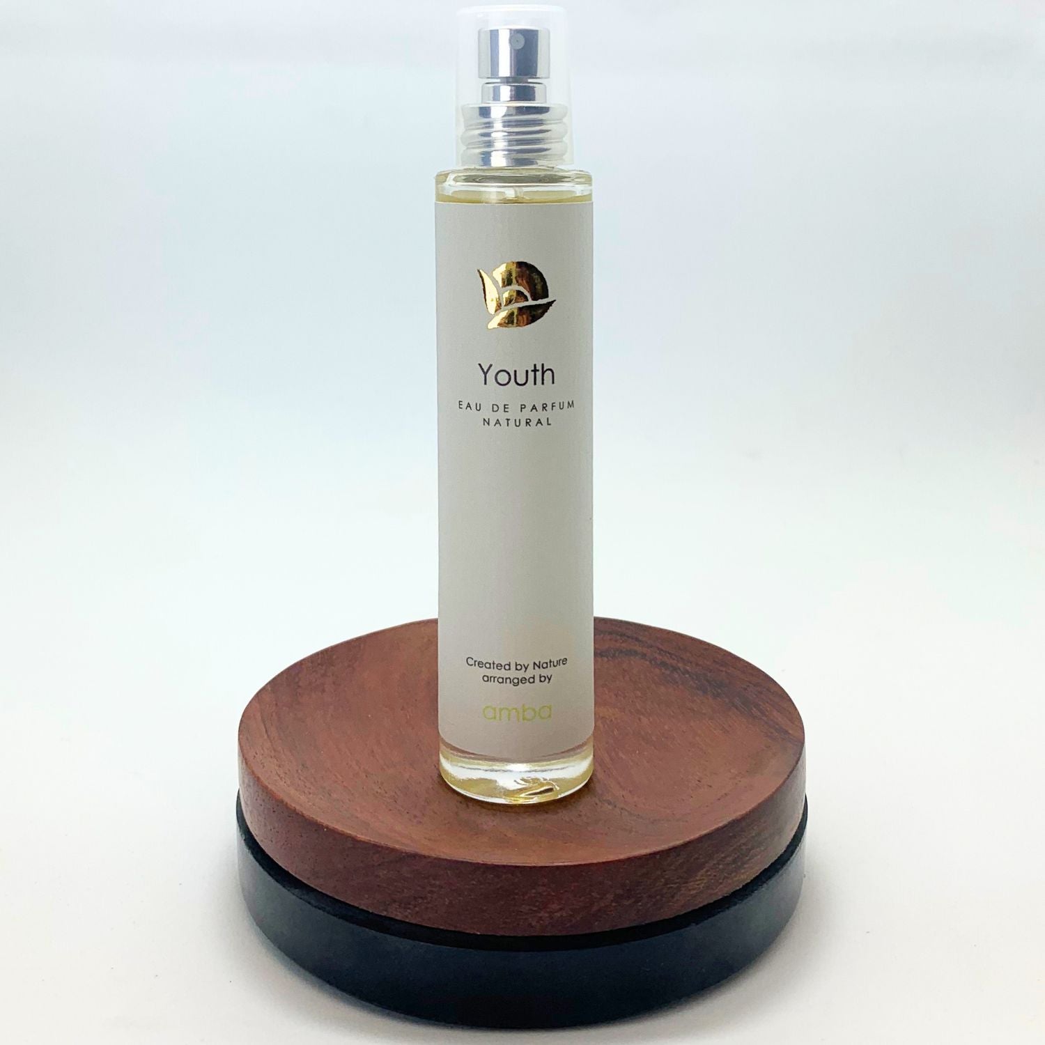 amba Youth Naturparfum Flakon auf Holzsockel vor weißem Hintergrund