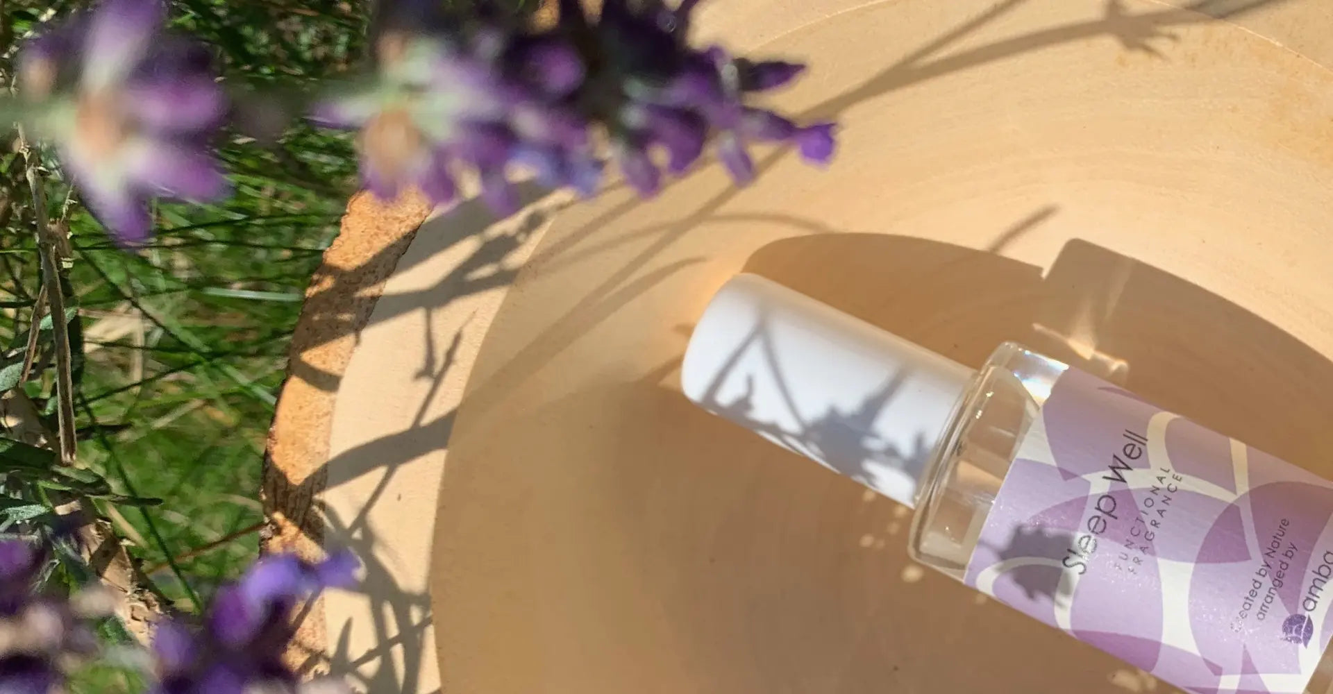 amba Sleep Well Functional Fragrances Flasche auf einem Holzhintergrund umgeben von Lavendel