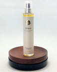 Flakon des Grace Naturparfums von amba auf Holzsockel vor weißem Hintergrund
