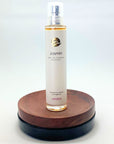 Flakon des Jasmin Naturparfums von amba auf Holzsockel vor weißem Hintergrund