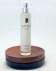 Flakon des Mystic Rose Naturparfums von amba auf Holzsockel vor weißem Hintergrund