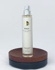 Flakon des Relax Naturparfums von amba auf Holzsockel vor weißem Hintergrund