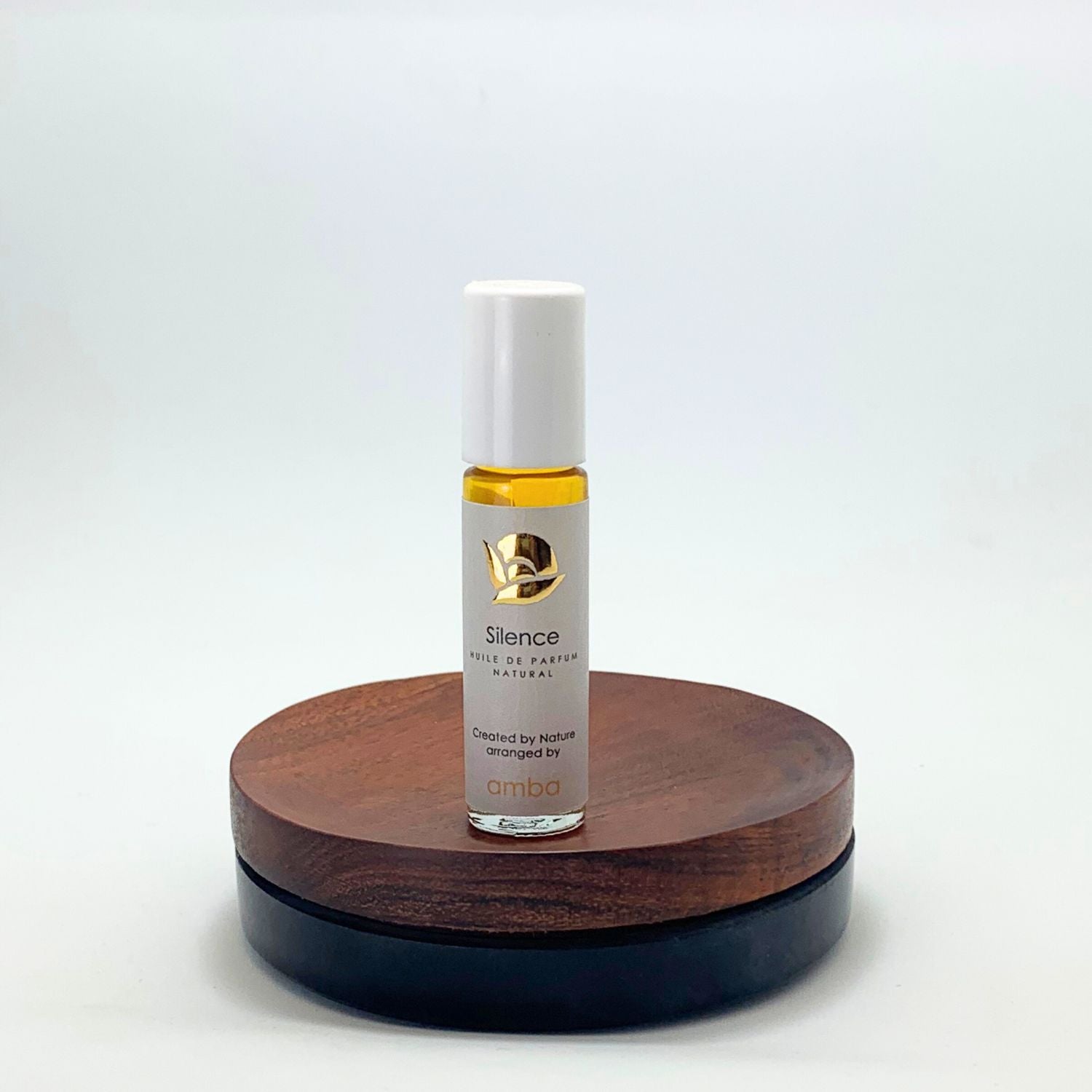 Roll-on Naturparfum Silence – Huile de Parfum von amba auf Holzsockel vor weißem Hintergrund